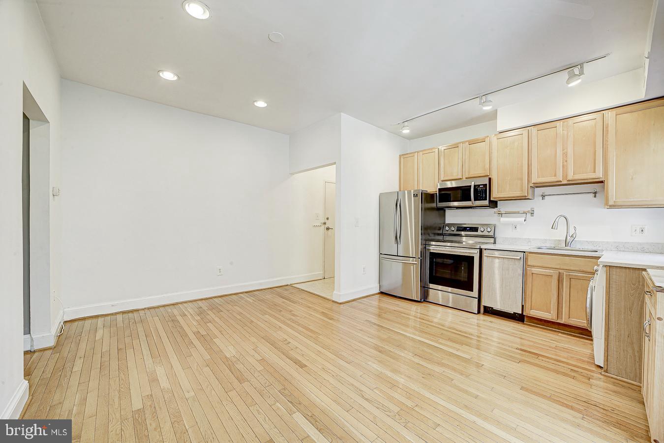 1401 Columbia Road Northwest, Unit 219 Washington, DC 20009 - Photo 6 of 33 a kitchen with stainless steel appliances a stove a sink and white cabinets with wooden floor