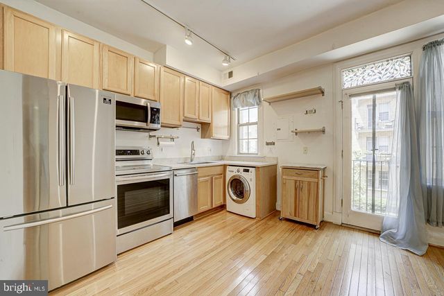a kitchen with stainless steel appliances a stove a sink a refrigerator white cabinets and wooden floor