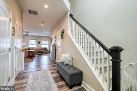 a kitchen with stainless steel appliances granite countertop a refrigerator a sink dishwasher a stove top oven a refrigerator with white cabinets and wooden floor