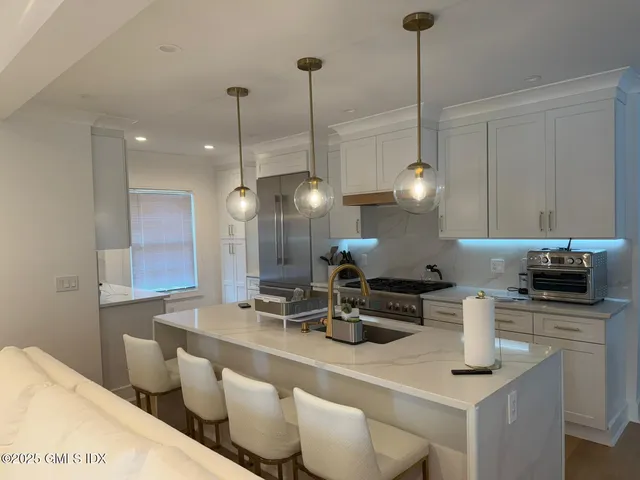 a kitchen with stainless steel appliances kitchen island granite countertop a sink a stove and a wooden floors