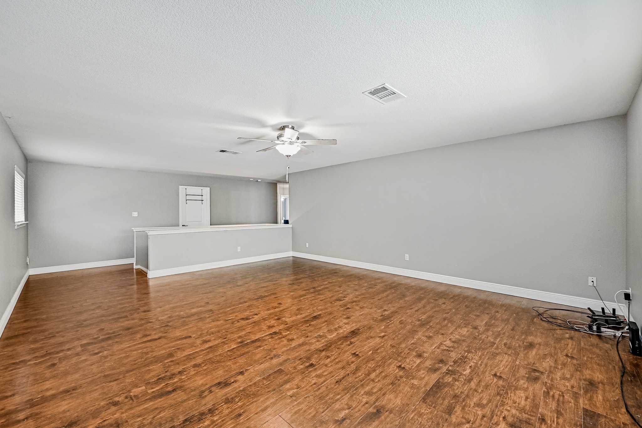 104 North Sumac Lane Georgetown, TX 78633 - Photo 27 of 40 A spacious living area with warm wood flooring and a refreshing ceiling fan invites comfortable gatherings.