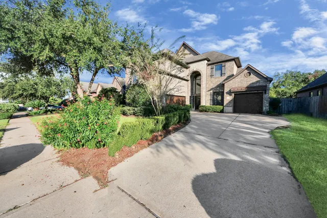 a front view of a house with a garden and trees