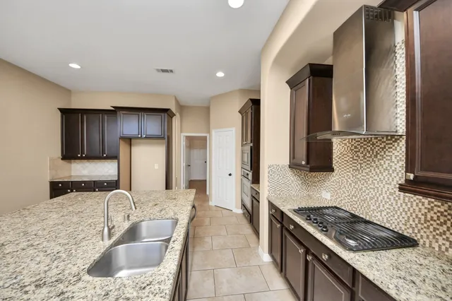 a large kitchen with granite countertop a sink and a stove top oven