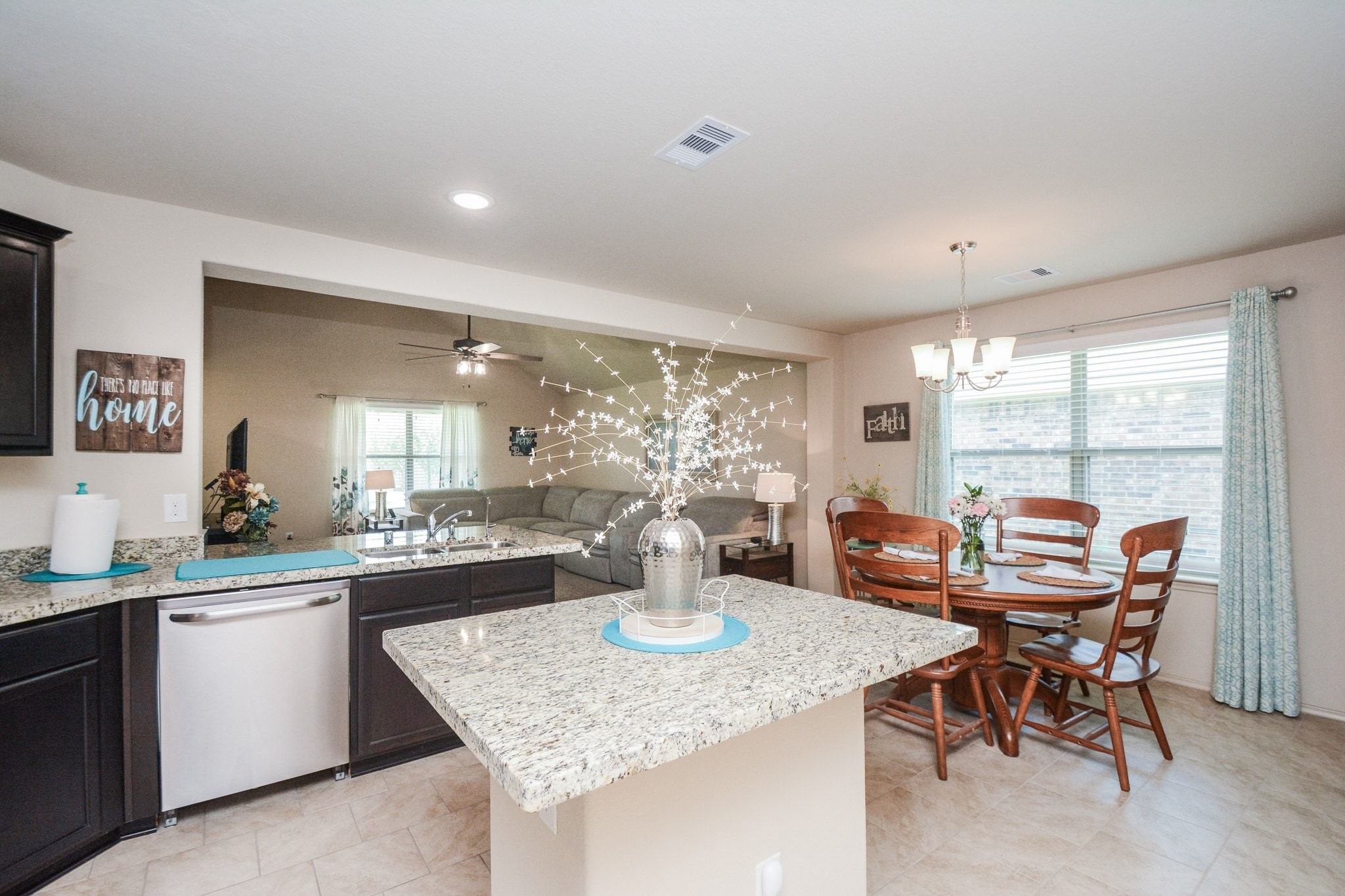 23318 Dukes Run Drive Spring, TX 77373 - Photo 2 of 41 This photo showcases an open-concept kitchen and dining area with granite countertops, dark cabinetry, and a cozy dining nook. The space is brightened by large windows and a modern chandelier, providing a welcoming atmosphere.