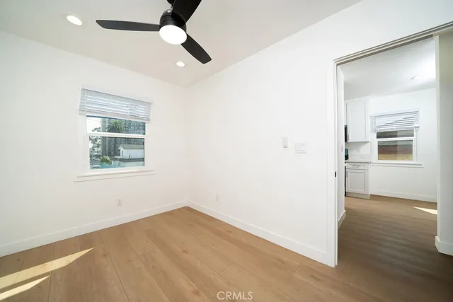 an empty room with wooden floor chandelier fan and windows