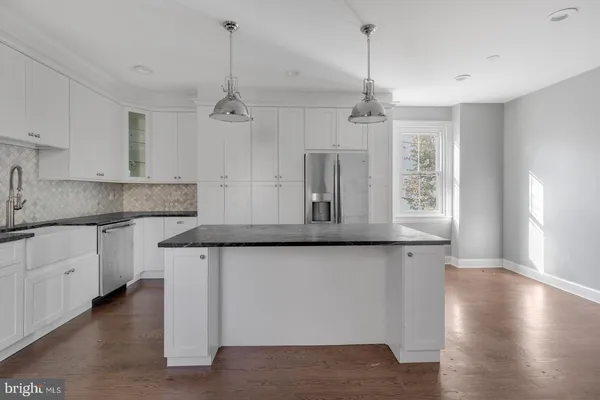 a kitchen with stainless steel appliances granite countertop a sink a window a refrigerator and white cabinets