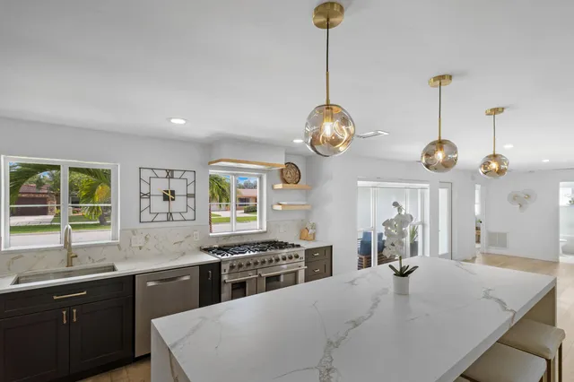 a kitchen with stainless steel appliances granite countertop a stove a sink dishwasher a dining table and chairs with wooden floor