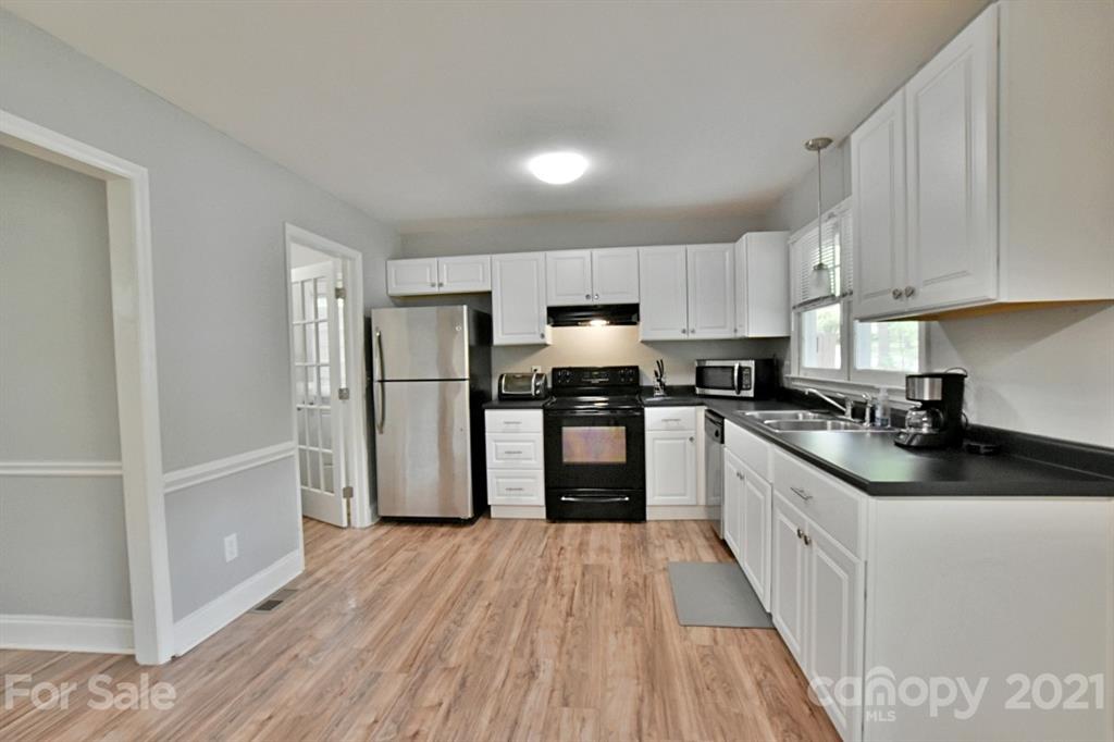 8108 Barncliff Road Charlotte, NC 28227 - Photo 11 of 25 a kitchen with granite countertop a refrigerator stove top oven and wooden floor