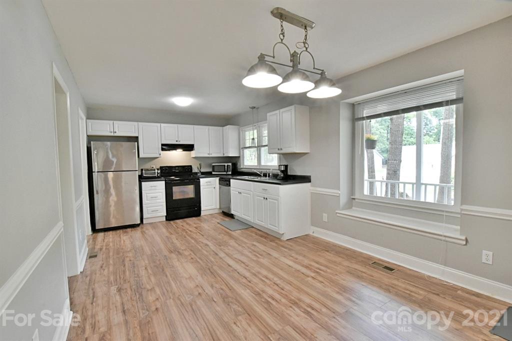 8108 Barncliff Road Charlotte, NC 28227 - Photo 9 of 25 a kitchen with stainless steel appliances granite countertop a refrigerator a sink dishwasher a stove and white cabinets with wooden floor