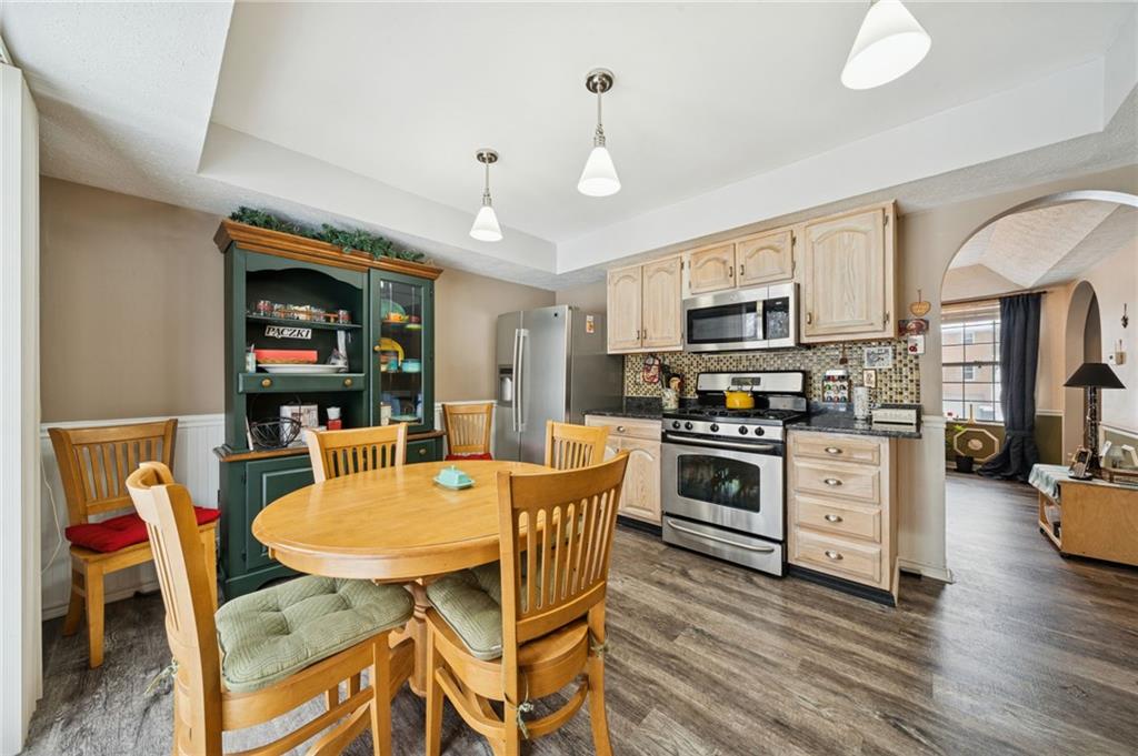 3151 Seneca Court Gibsonia, PA 15044 - Photo 4 of 38 a kitchen with stainless steel appliances granite countertop a stove a sink dishwasher a dining table and chairs with wooden floor