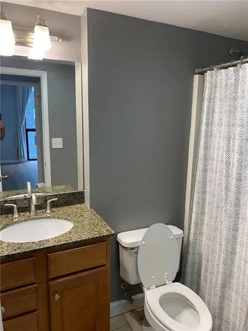 a bathroom with a granite countertop toilet sink and mirror