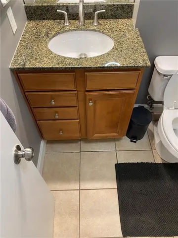 a bathroom with a granite countertop sink a toilet and mirror