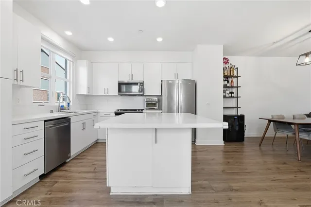 a kitchen with kitchen island white cabinets and stainless steel appliances