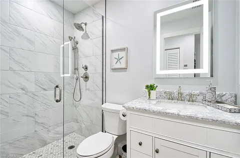 a bathroom with a granite countertop sink mirror vanity and toilet
