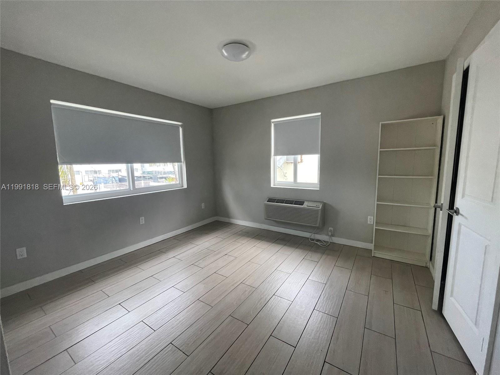 625 77th Street, Unit 2 Miami Beach, FL 33141 - Photo 13 of 17 an empty room with wooden floor and windows