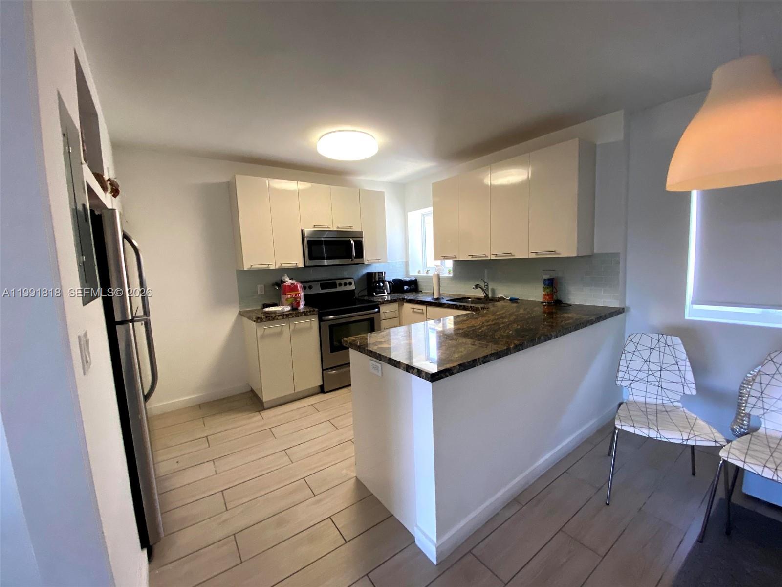 625 77th Street, Unit 2 Miami Beach, FL 33141 - Photo 5 of 17 a kitchen with stainless steel appliances granite countertop a refrigerator a stove top oven a sink and dishwasher