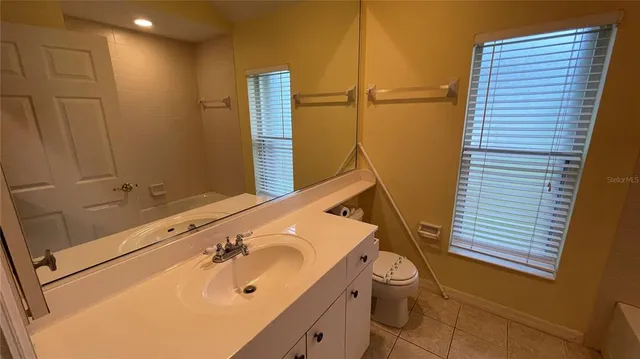 a bathroom with a sink and mirror with bathtub