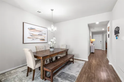 a dining room with wooden floor a chandelier a wooden table and chairs
