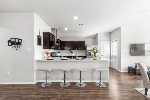 a kitchen with stainless steel appliances a microwave a stove a refrigerator a sink dishwasher and white cabinets with wooden floor