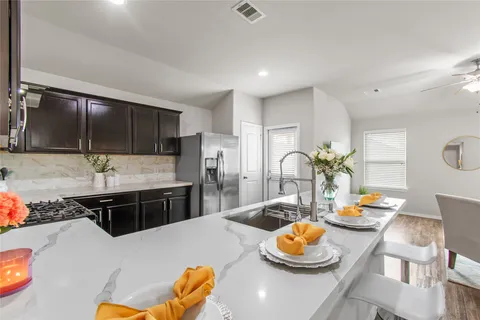 a kitchen with stainless steel appliances granite countertop a sink a stove a dining table and chairs