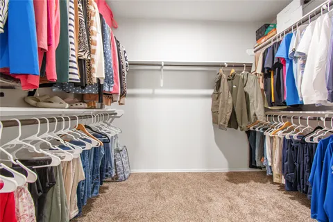a view of walk in closet with clothes and shoes