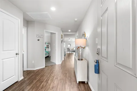 a hallway with wooden floor white walls and stairs