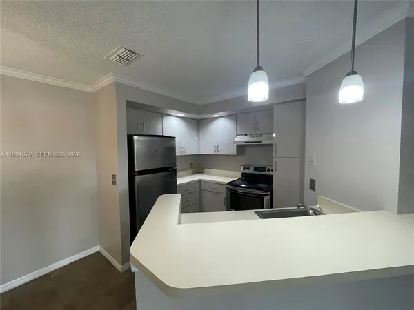 a large kitchen with a refrigerator a stove and wooden floor