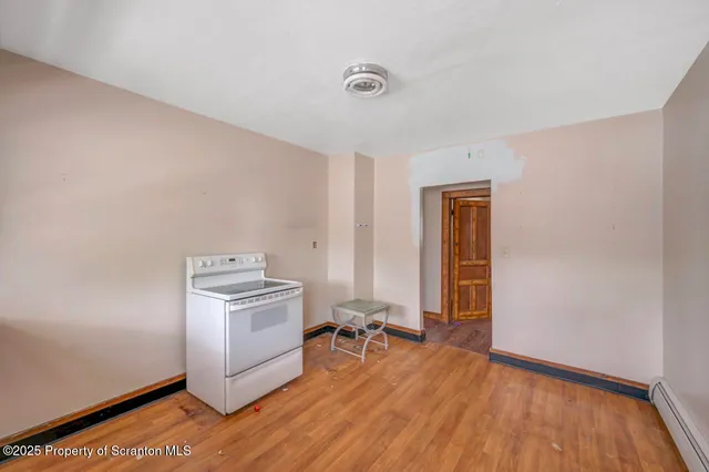 an empty room with wooden floor closet and windows