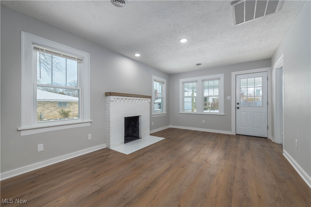 218 Roxboro Road Vermilion, OH 44089 - Photo 8 of 50 Unfurnished living room with a textured ceiling, a fireplace, dark wood-type flooring, and recessed lighting