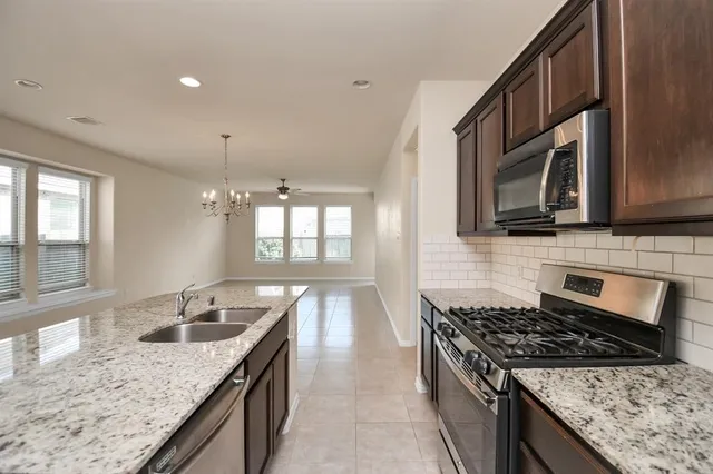 a kitchen with granite countertop stainless steel appliances sink stove microwave and cabinets