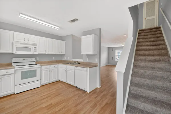 a kitchen with cabinets and wooden floor