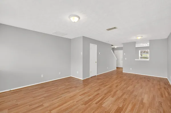 a view of an empty room with wooden floor and a window