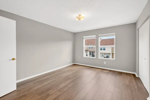 an empty room with wooden floor and windows