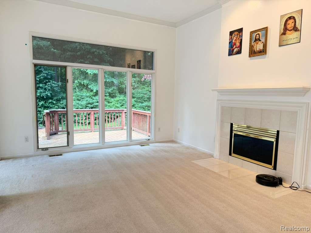 1154 Bluebird Drive Rochester, MI 48307 - Photo 10 of 34 Spacious room featuring a fireplace with a tile surround and mantel, a wide sliding glass door, an upper transom window, and a wooden deck
