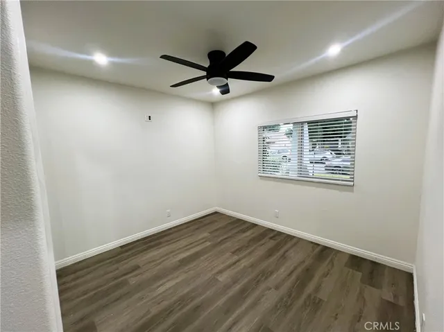 an empty room with wooden floor and a ceiling fan