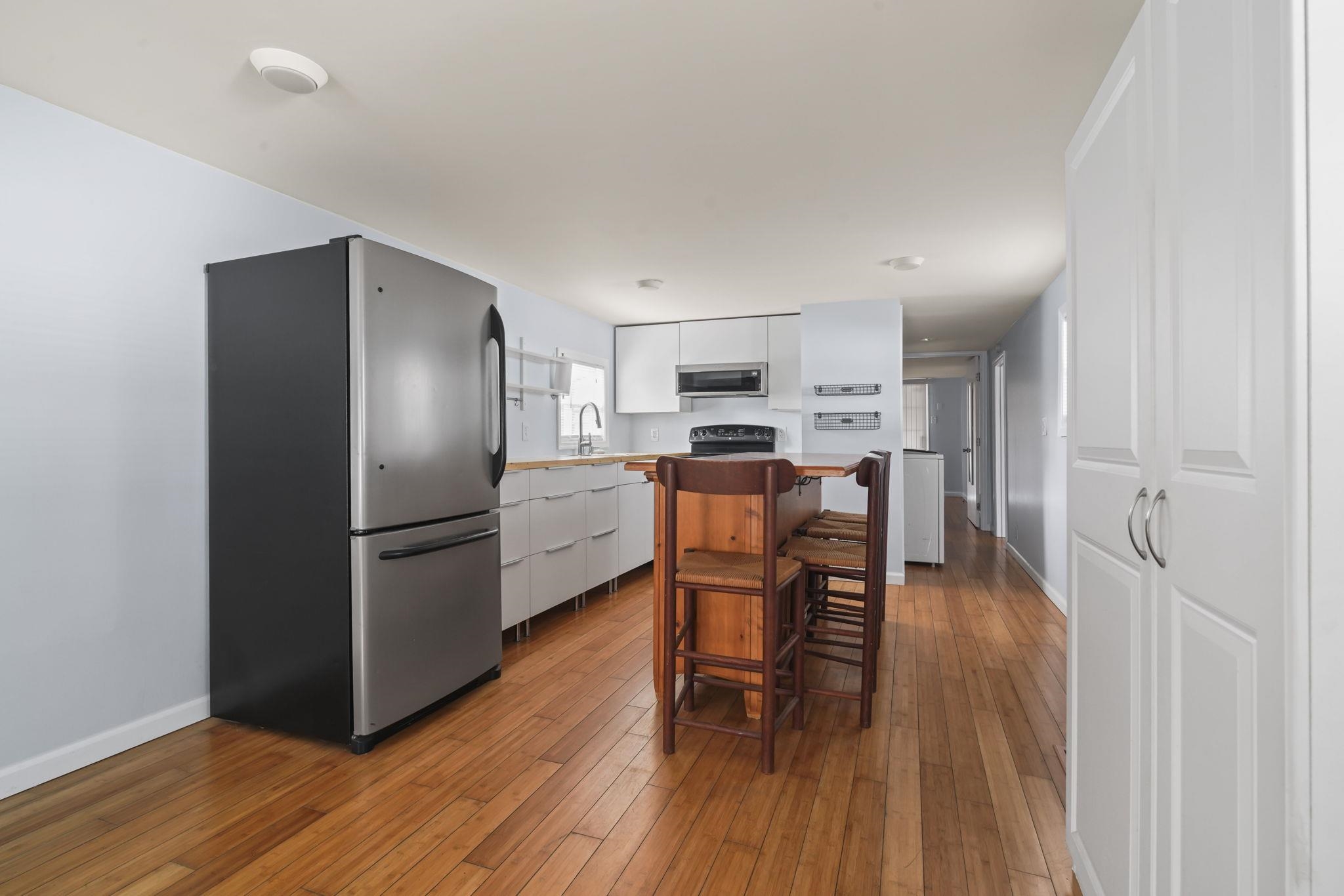 45 Shamrock Circle Murrells Inlet, SC 29576 - Photo 21 of 32 Kitchen featuring white cabinetry, appliances with stainless steel finishes, a kitchen bar, light countertops, and light wood-style flooring