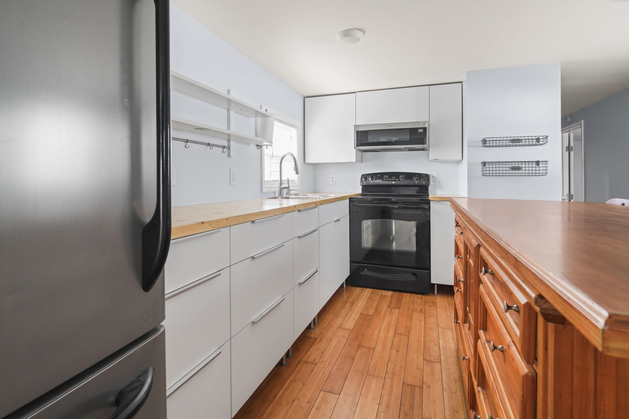45 Shamrock Circle Murrells Inlet, SC 29576 - Photo 22 of 32 Kitchen with freestanding refrigerator, white cabinetry, black range with electric cooktop, light wood finished floors, and exhaust hood