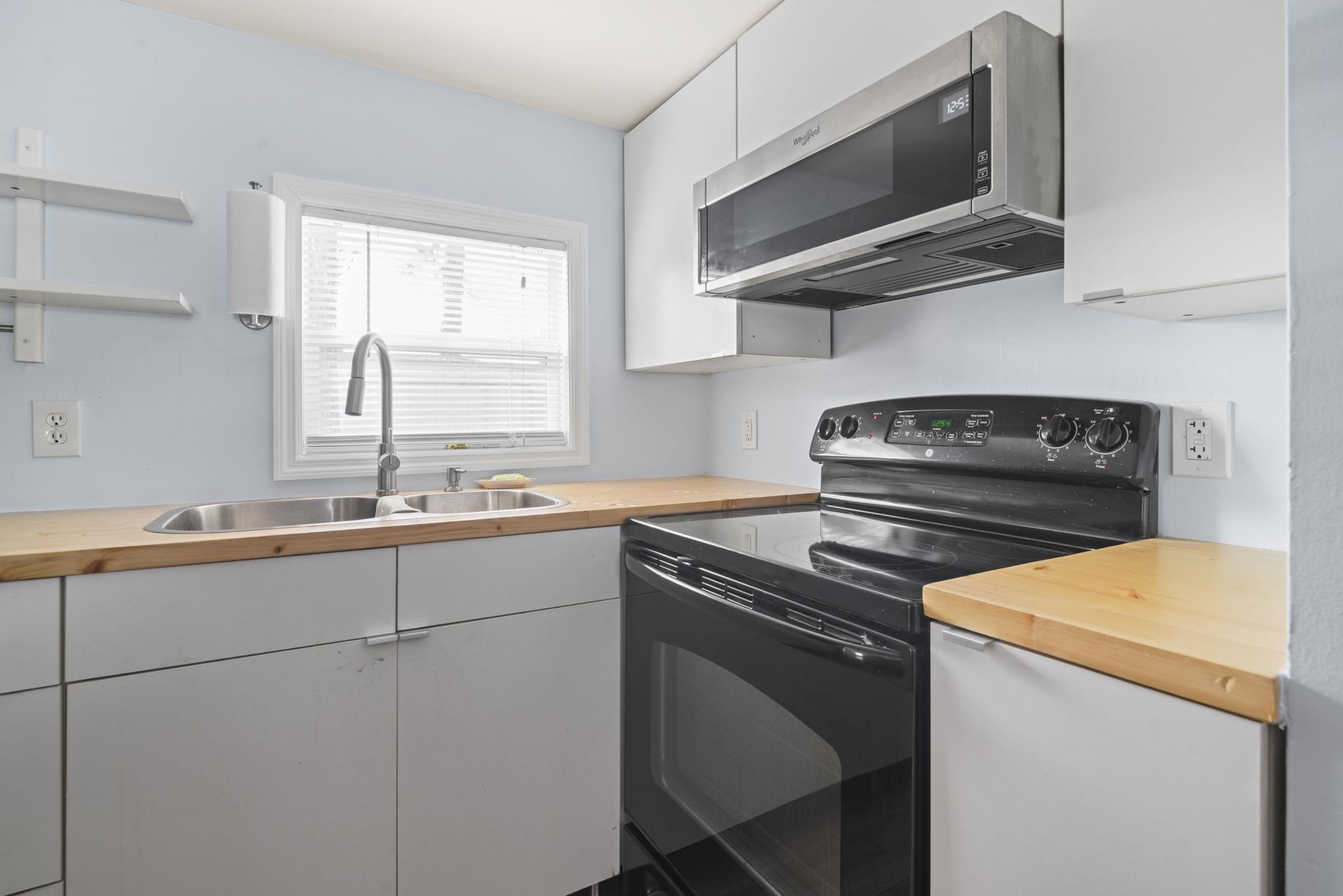 45 Shamrock Circle Murrells Inlet, SC 29576 - Photo 24 of 32 Kitchen with white cabinets, black electric range oven, stainless steel microwave, and butcher block countertops