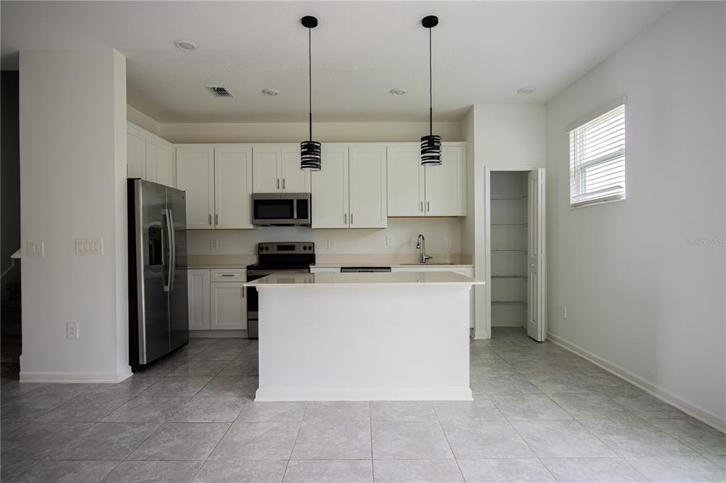 2340 Brook Marsh Loop Kissimmee, FL 34747 - Photo 27 of 53 a kitchen with a refrigerator a microwave oven a stove and white cabinets
