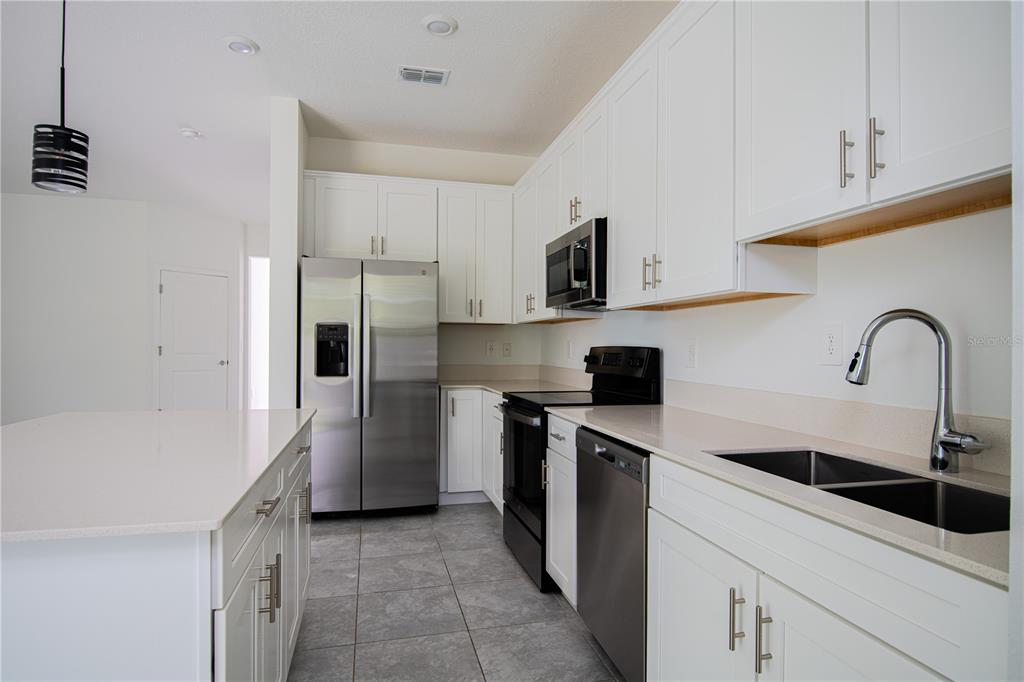 2340 Brook Marsh Loop Kissimmee, FL 34747 - Photo 29 of 53 a kitchen with stainless steel appliances a sink dishwasher a refrigerator and a stove with wooden floor