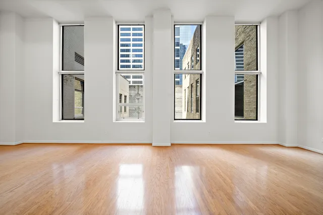 a view of an empty room with window and wooden floor