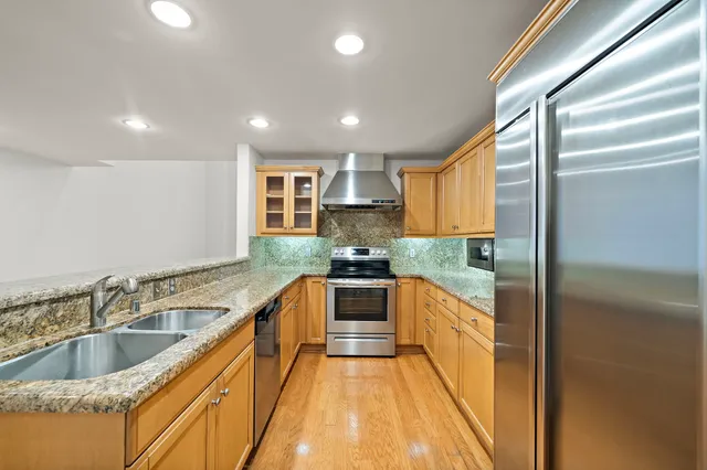 a large kitchen with stainless steel appliances granite countertop a sink and a refrigerator