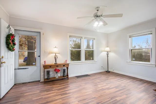 a view of an empty room with a window and wooden floor