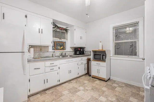 a kitchen with granite countertop white cabinets and white stainless steel appliances