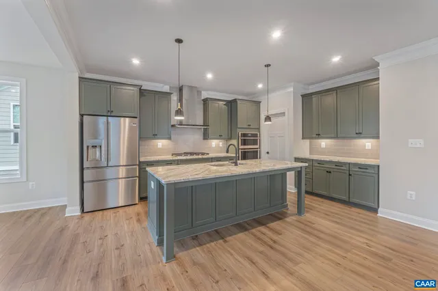 a kitchen with stainless steel appliances granite countertop a refrigerator a sink dishwasher a stove and a refrigerator with wooden floor