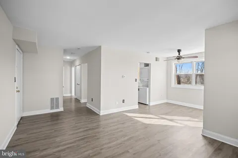 a view of empty room with wooden floor and kitchen