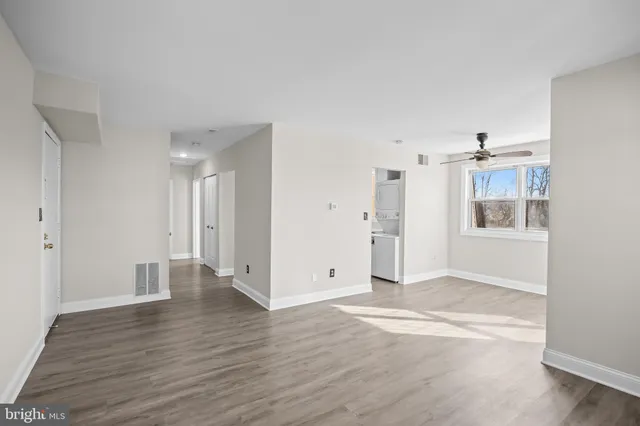 a view of empty room with wooden floor and kitchen