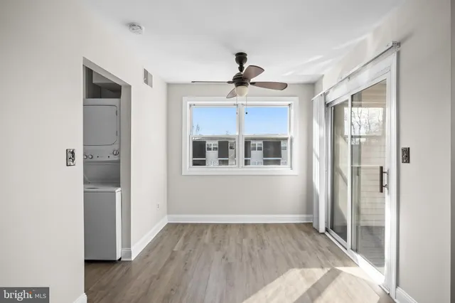 a view of empty room with wooden floor and fan