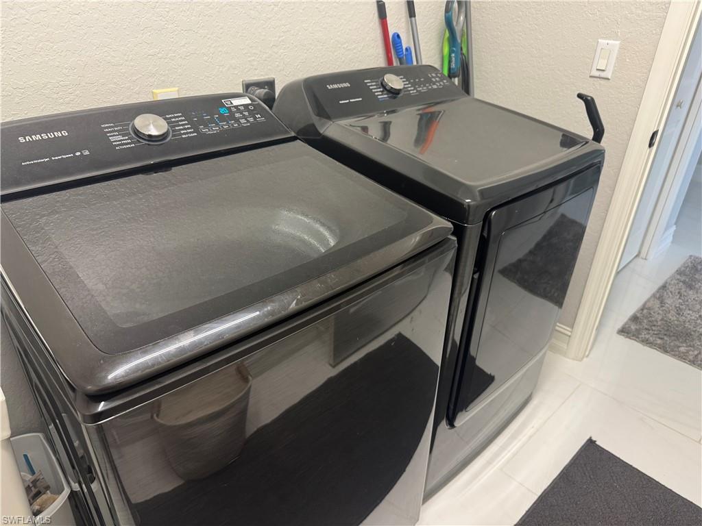 18445 Royal Hammock Boulevard Naples, FL 34114 - Photo 46 of 50 Laundry area featuring a textured wall, washing machine and dryer, and light tile patterned floors