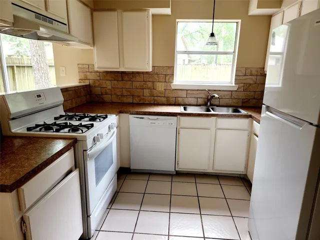 a kitchen with a sink a stove and white cabinets